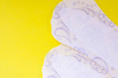 İki günlük kadın pedleri veya Sıhhi Peçete (havlu) yukarıdan sarı tek tip arka plan görünümüyle etiketleri veya üstbilgileri için yarım fotoğrafın açık alan vardır. Kadın hijyen ürünleri vulvovaginal sağlık için