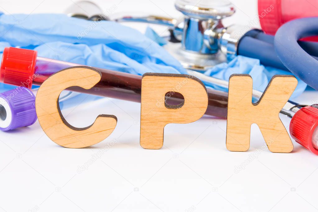 Abbreviation or acronym of CPK, in laboratory, scientific, research or medical practice means creatine phosphokinase (creatine kinase), is in foreground with laboratory test tubes, medical stethoscope