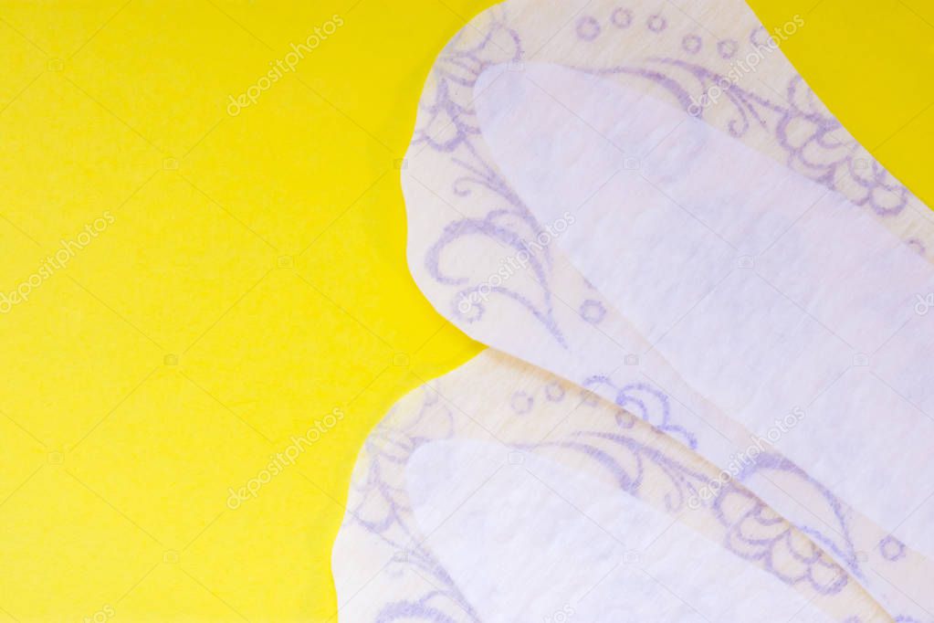 Two daily female pads or sanitary napkin (towel) are on yellow uniform background view from above with clear area of half photo for labels or headers. Female hygienic products for vulvovaginal health