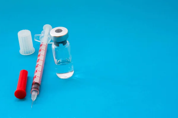 注射器和玻璃安瓿的疫苗 胰岛素 抗生素或其他药物是在蓝色背景与空白区域的头 医学或糖尿病治疗疫苗的概念照片 — 图库照片