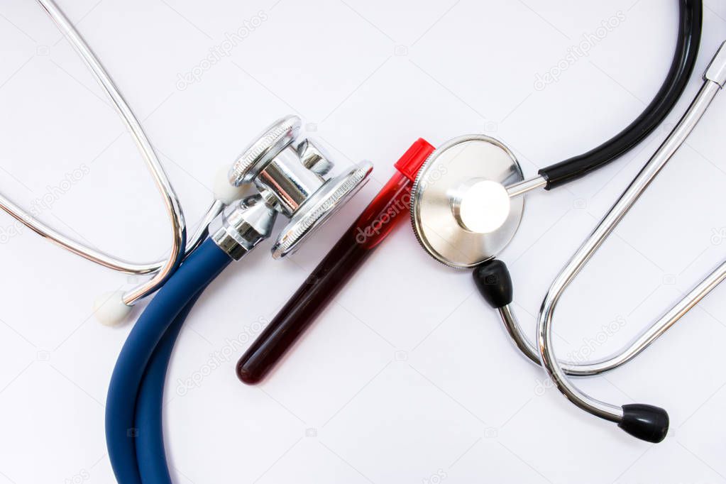 Medical concept in Hematology, study of blood, blood-forming organs and blood diseases. Lab test tube with blood of patient is surrounded by two heads of stethoscopes, which examined it