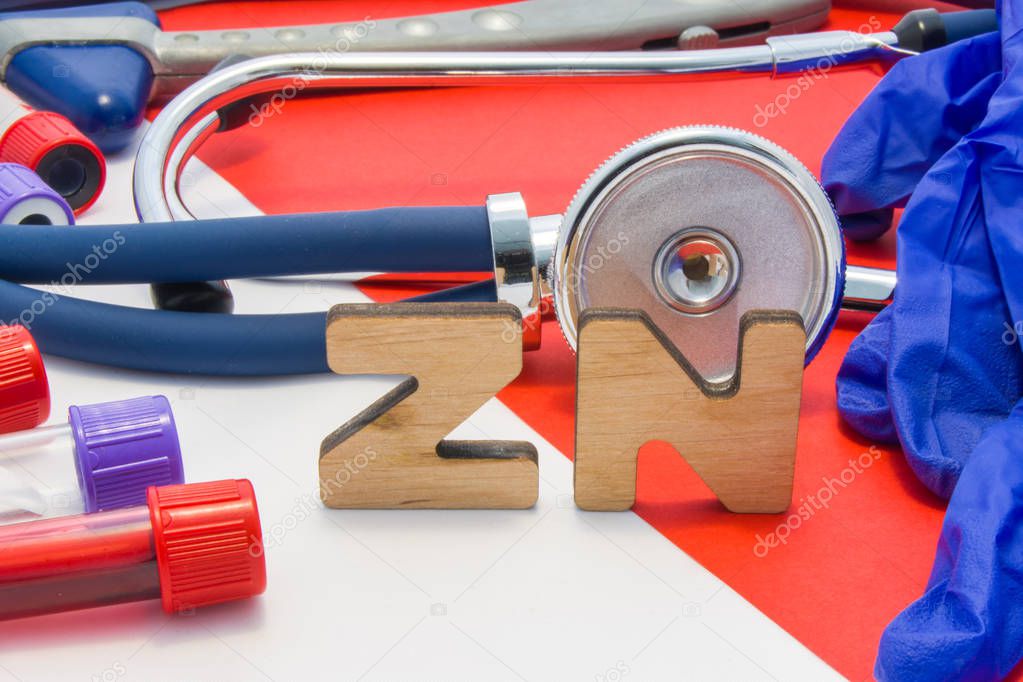 ZN medical abbreviation meaning total zinc in body or blood in laboratory diagnostics on red background. Chemical name of ZN is surrounded by medical laboratory test tubes with blood, stethoscope