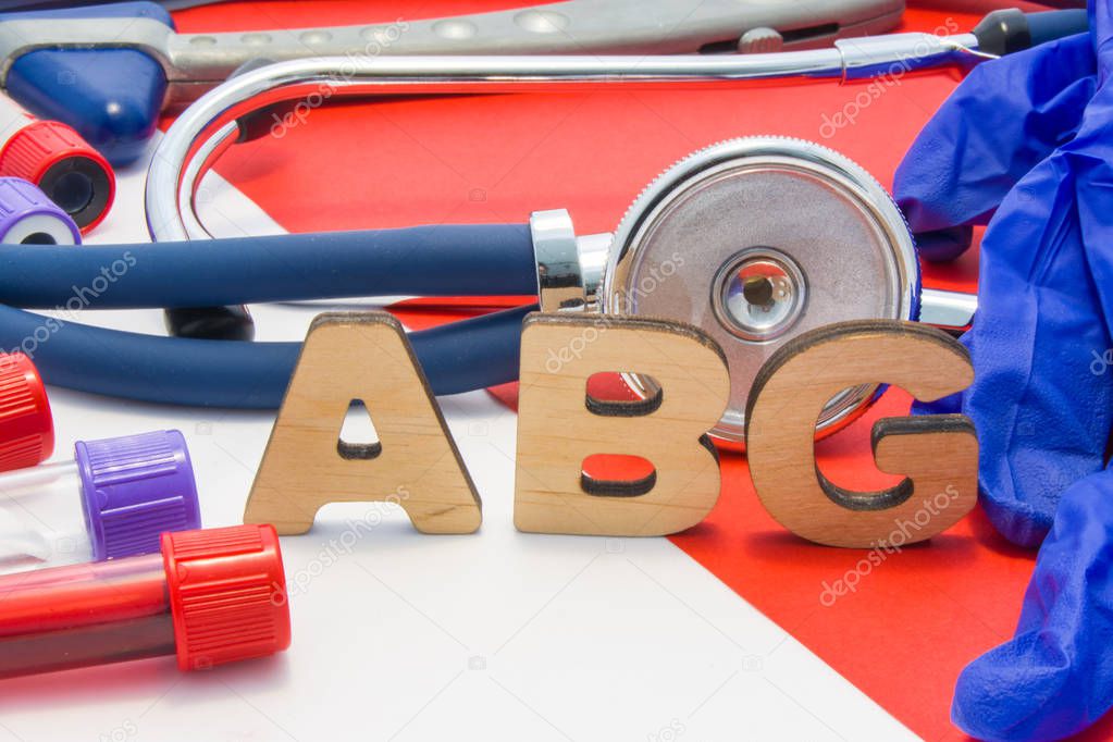ABG medical abbreviation meaning arterial blood gas in blood in laboratory diagnostics on red background. Chemical name of ABG is surrounded by medical laboratory test tubes with blood, stethoscope