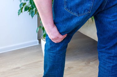 Photo concept pain in popliteal fossa or the back of the knee, knee joints or ligaments, cruciate for example. Man standing with his hand over area, which is located on back of  leg   clipart