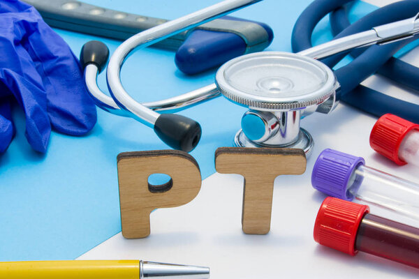 PT Medical lab acronym, meaning Prothrombin Time in blood. Letters that make word of PT, located near test tubes with blood, stethoscope and other diagnostic tools and devices, latex gloves