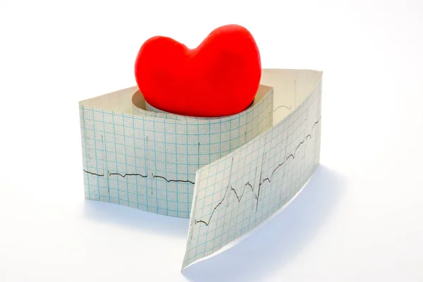 アイデア写真不整脈および正常な心臓のリズムの障害に関連する心臓病 モデル赤い中心は白い背景のペーパー心電図のロールの上にある — ストック写真