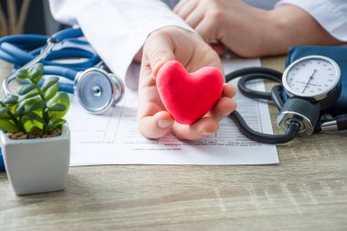 Doktor iç tıp ve kardiyolog elinde tutan ve Tıbbi Danışma sırasında kırmızı kart kalp hasta rakam gösterir. Kalp, tanı ve tedavi nedenlerinin açıklaması