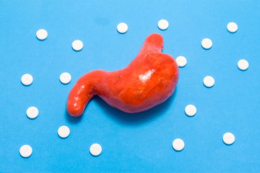 mide 3D anatomik model süs Polka noktalar olarak beyaz haplar ile çevrili mavi arka plan üzerinde. Farmakolojik tablet tarafından tıbbi kavram mide hastalığı tedavisinde, farmakoterapi, kemoterapi