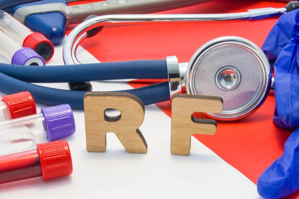 RF medical abbreviation meaning rheumatoid factor in blood in laboratory diagnostics on red background. Chemical name of RF is surrounded by medical laboratory test tubes with blood, stethoscope