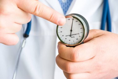 Doktor hasta ve noktaları parmak mekanik sphygmomanometer ok, hangi sırayla kan basıncı yüksek sayıda gösterir gösterir. Konsept Fotoğraf tedavisi ve yüksek basınç önleme