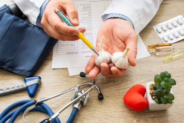 Doktor beslenme uzmanı elinde düzenlenen konsültasyon sırasında ve hasta sarımsak ampul gösterir. Danışmanlık ve gıda ve diyet sarımsak kullanımının açıklaması, sağlık yararları, vücut ve organlar üzerindeki etkisi, bağışıklık