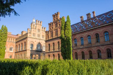 Yeşillik yan görünümünde çok renkli kiremitler tarafından desenli süslenmiş çatı ile binalar ve kampüs. Chernivtsi Mimarlık Üniversitesi 