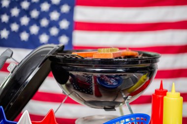 Küçük yuvarlak kömür ızgara ve 4 Temmuz süslemeleri Amerikan üzerinde arka plan bayrak.