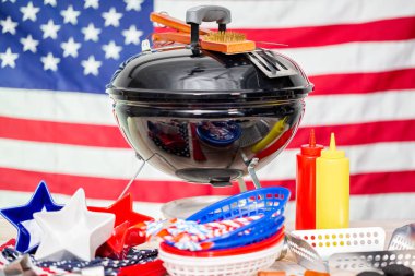 Küçük yuvarlak kömür ızgara ve 4 Temmuz süslemeleri Amerikan üzerinde arka plan bayrak.