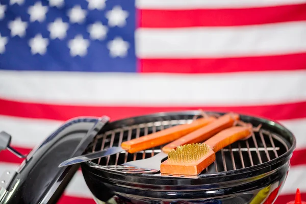 stock image Small round charcoal grill and July 4th decorations on American flag background.