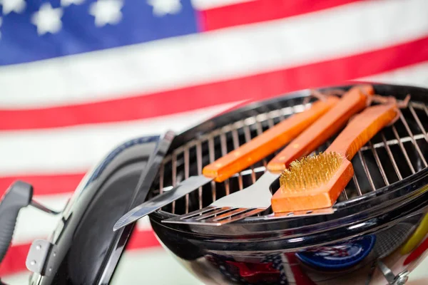 stock image Small round charcoal grill and July 4th decorations on American flag background.