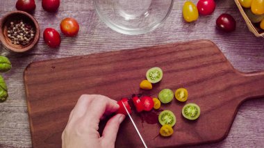 Adım adım. Hatıra cherry domates ahşap kesme tahtası üzerinde Dilimleme.