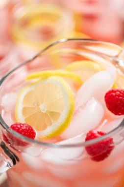 Frambuazlı limonata taze limon ve cam sürahi içinde ahududu ile süslenmiş.