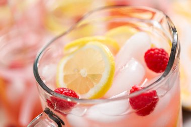 Frambuazlı limonata taze limon ve cam sürahi içinde ahududu ile süslenmiş.