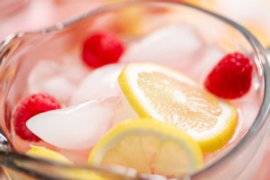 Frambuazlı limonata taze limon ve cam sürahi içinde ahududu ile süslenmiş.