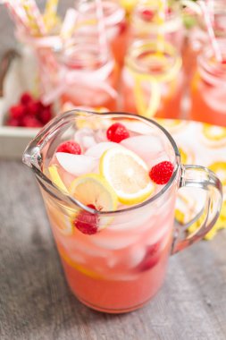 Frambuazlı limonata taze limon ve cam sürahi içinde ahududu ile süslenmiş.