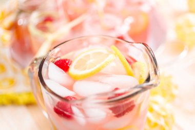 Frambuazlı limonata taze limon ve cam sürahi içinde ahududu ile süslenmiş.