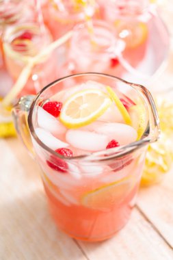 Frambuazlı limonata taze limon ve cam sürahi içinde ahududu ile süslenmiş.