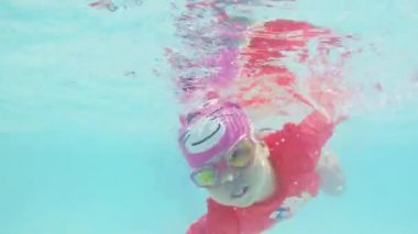 Küçük kız eğleniyor açık yüzme havuzunda su altında yüzmek