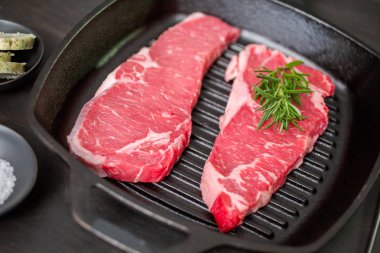 Dökme demir tavada ham New York şerit biftek.