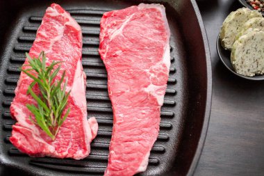 Dökme demir tavada ham New York şerit biftek.