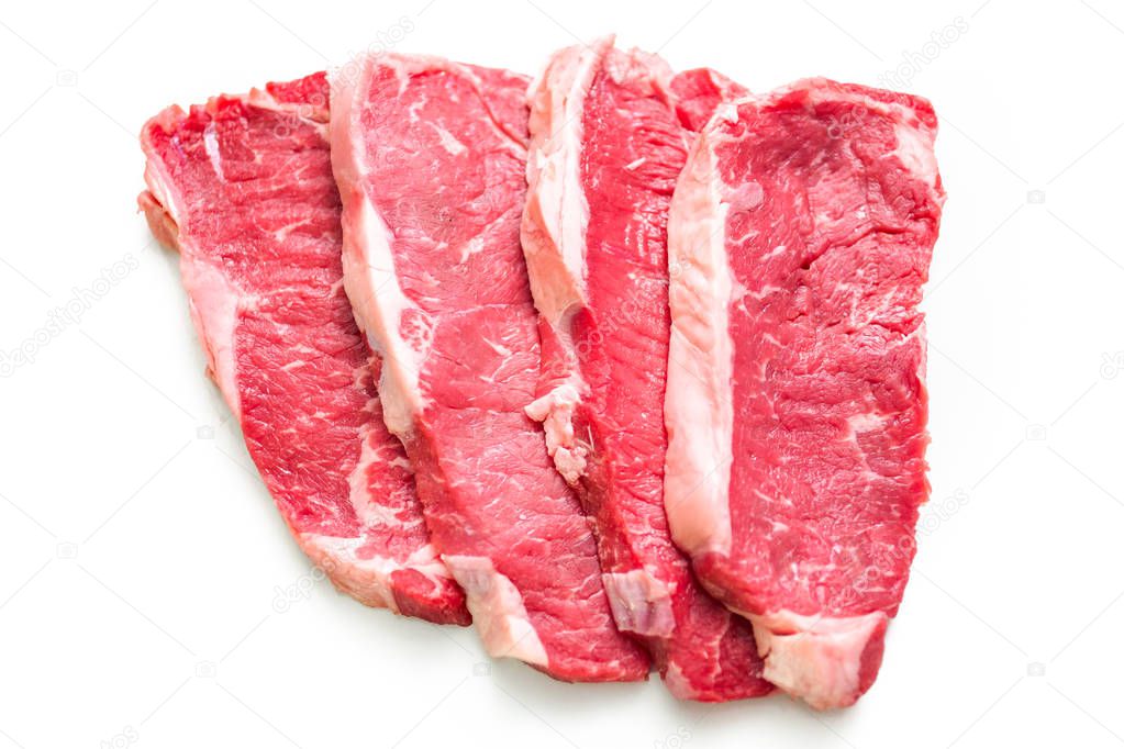 Raw New York strip steaks on a white background.