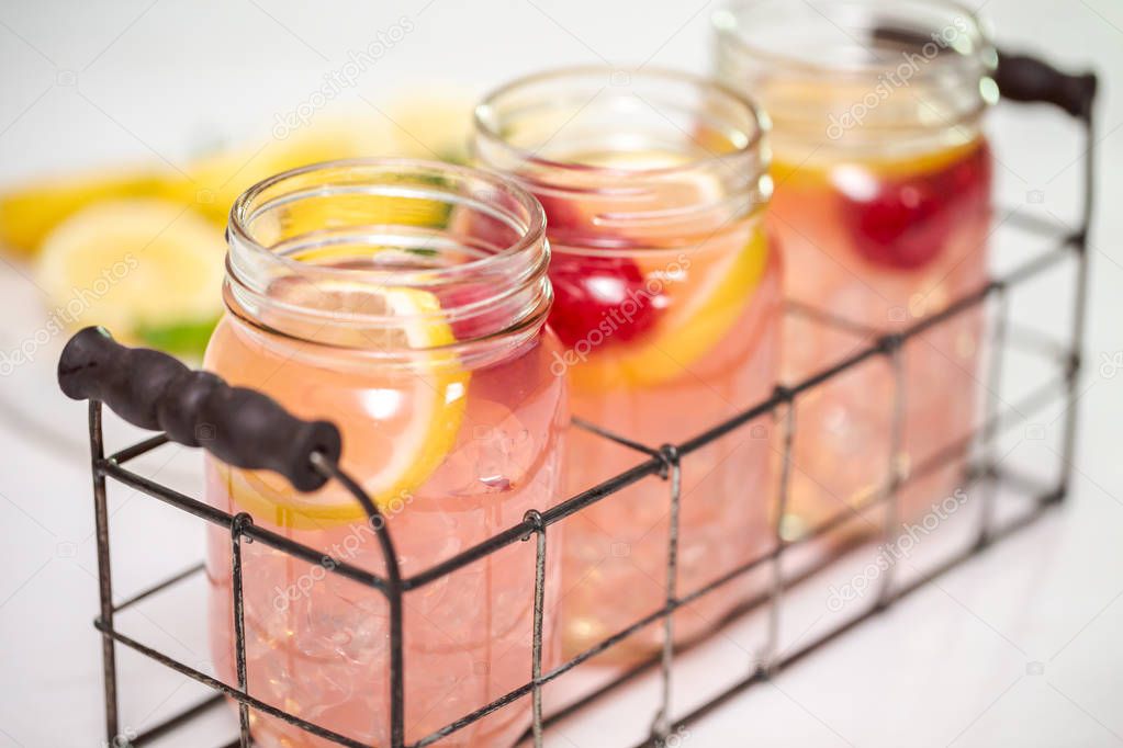 Raspberry lemonade in drinking mason jars on a white table.