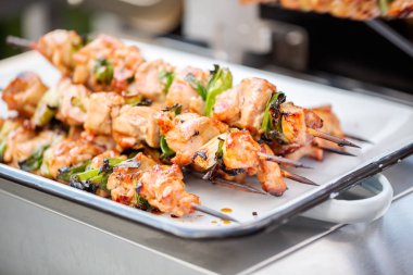 Adım adım. Tavuk yakitori açık gaz ızgara yanındaki bir beyaz metal servis tepsi.