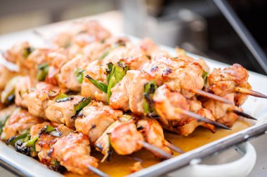 Adım adım. Tavuk yakitori açık gaz ızgara yanındaki bir beyaz metal servis tepsi.