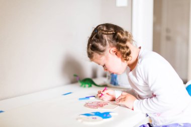 Küçük kız evde masasında çizim.