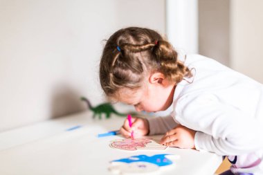 Küçük kız evde masasında çizim.