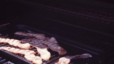 Dökme demir kalbur içinde açık gaz ızgara üzerinde ızgara domuz pastırması şeritler