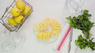 Adım adım. Beyaz ahşap kesme tahtası üzerinde taze organik limon Dilimleme.