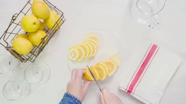 一歩一歩 白い木製のまな板で新鮮な有機レモンをスライス — ストック写真