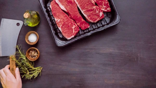 Siyah plastik et ambalaj kapsayıcısında ham New York şerit biftek.