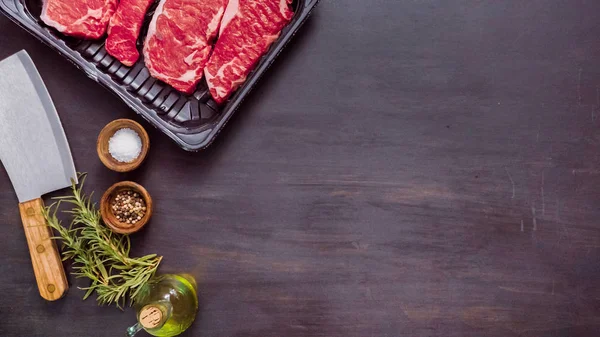 Siyah plastik et ambalaj kapsayıcısında ham New York şerit biftek.