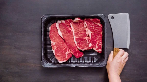 Siyah plastik et ambalaj kapsayıcısında ham New York şerit biftek.