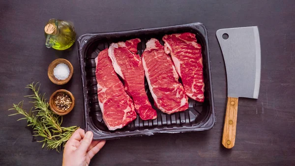 Siyah plastik et ambalaj kapsayıcısında ham New York şerit biftek.