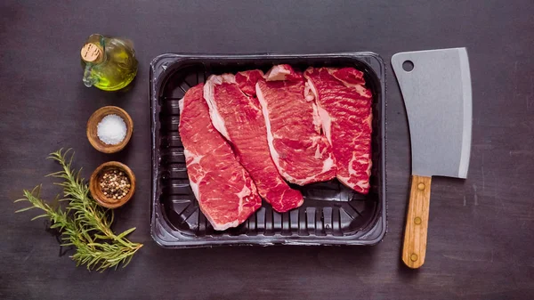 Siyah plastik et ambalaj kapsayıcısında ham New York şerit biftek.