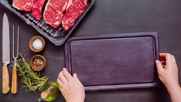 Siyah plastik et ambalaj kapsayıcısında ham New York şerit biftek.