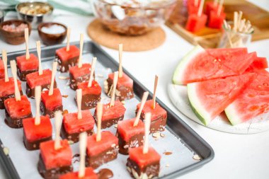 Çikolata ve sprinked deniz tuzu ve badem ile daldırma karpuz mezeler hazırlanıyor.