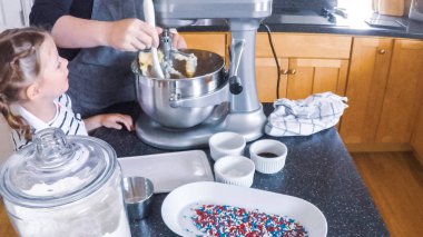 Adım adım. Anne ve kızı mutfakta şekerli kurabiye pişirme.