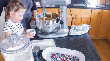 Adım adım. Anne ve kızı mutfakta şekerli kurabiye pişirme.