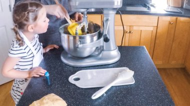 Adım adım. Anne ve kızı mutfakta şekerli kurabiye pişirme.