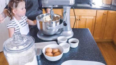 Adım adım. Anne ve kızı mutfakta şekerli kurabiye pişirme.